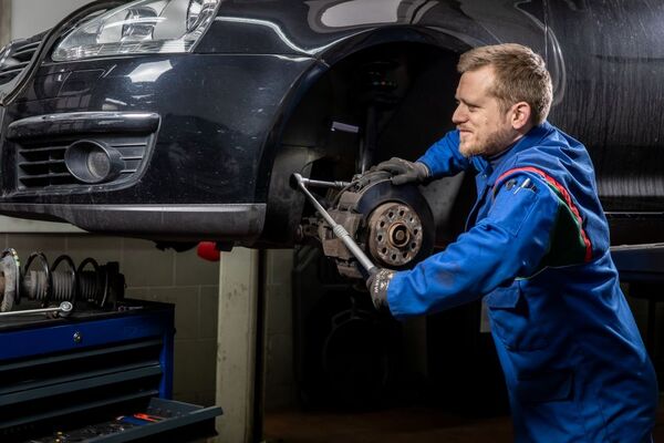 Kfz-Mechaniker wechselt Autobremsen in einer Werkstatt für professionelle Autoreparatur.